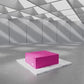 Pink rectangular box displayed on a pedestal in a modern, bright, minimalist showroom.