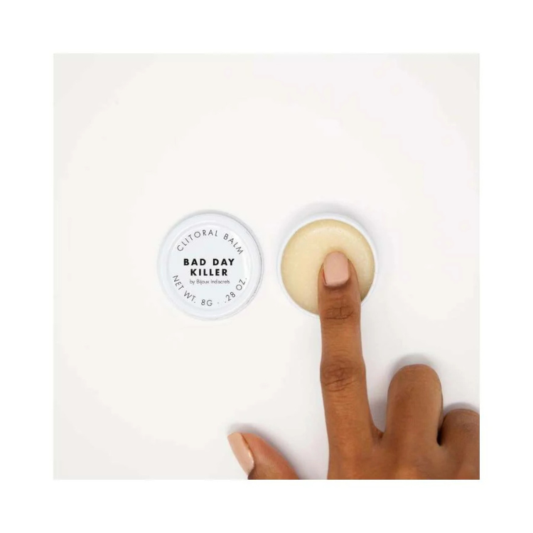 Hand applying Bijoux Indiscrets Clitherapy Bad Day Killer clitoral balm on a white background