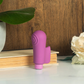Purple silicone bullet vibrator and sleeve on a table near a plant and white flower
