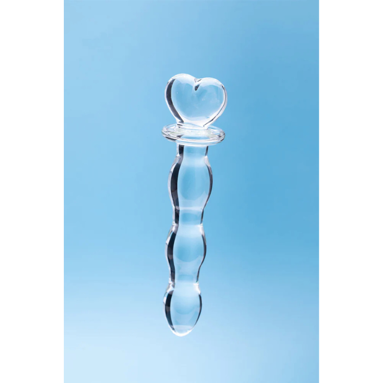 Clear glass toy with heart-shaped handle on light blue background, House of Vices wellness product