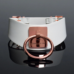 White faux leather choker with rose gold ring and Coquette branding on dark background