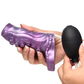 Hand holding purple silicone penis enhancer with siphon tentacle design and black bulb pump