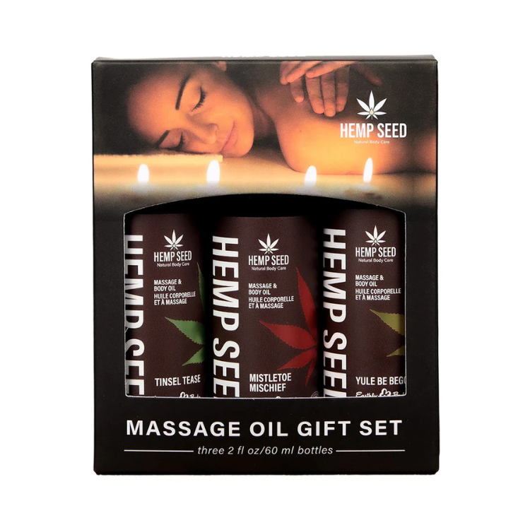 Earthly Body Hemp Seed Holiday Massage Oil Gift Set with Tinsel Tease, Mistletoe Mischief, Yule Be Begging oils in holiday packaging.