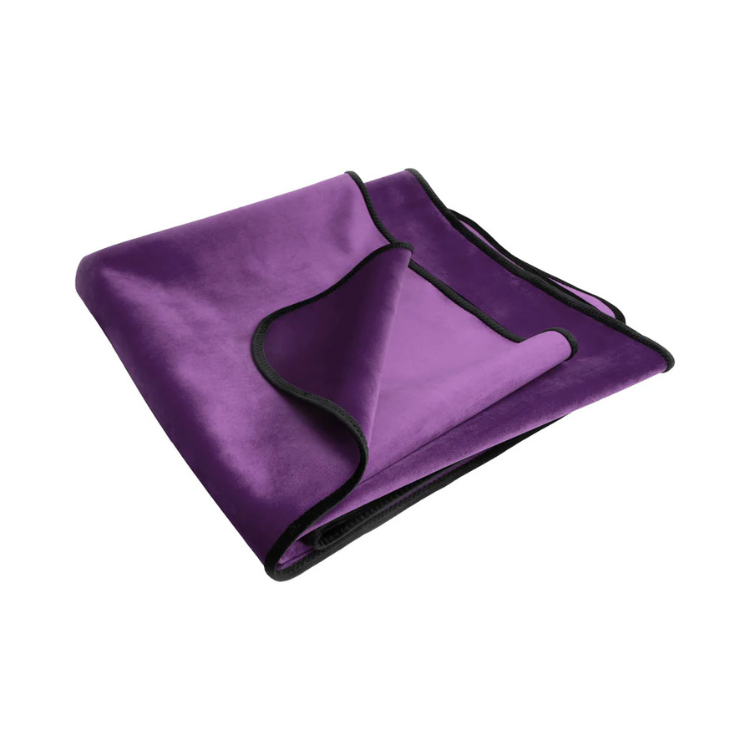 Folded purple waterproof travel throw blanket with black trim on a white background