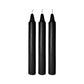 Three tall black taper candles with white wicks on a white background.