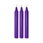 Three tall purple massage candles with white wicks on a white background.