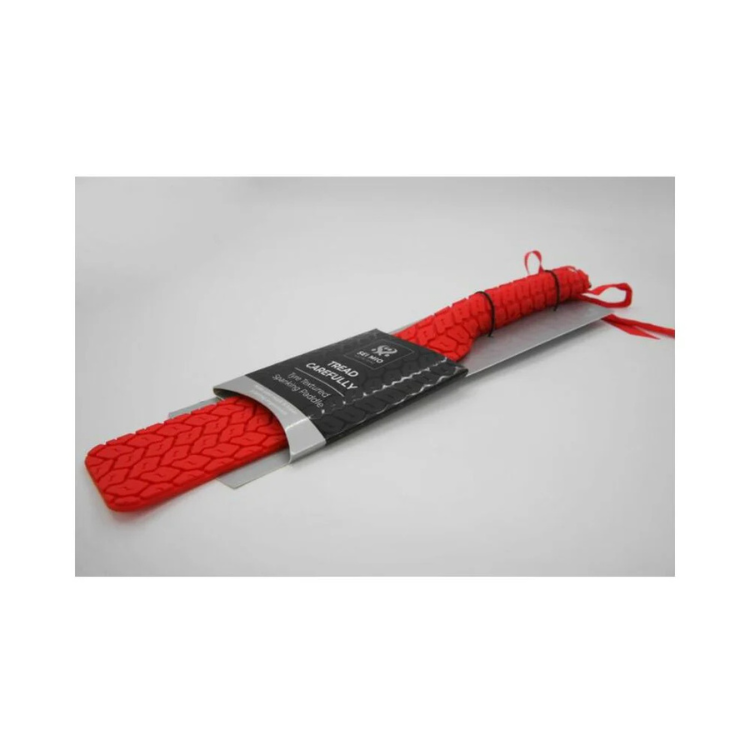 Red silicone paddle with textured tire pattern and wrist loop for adult roleplay