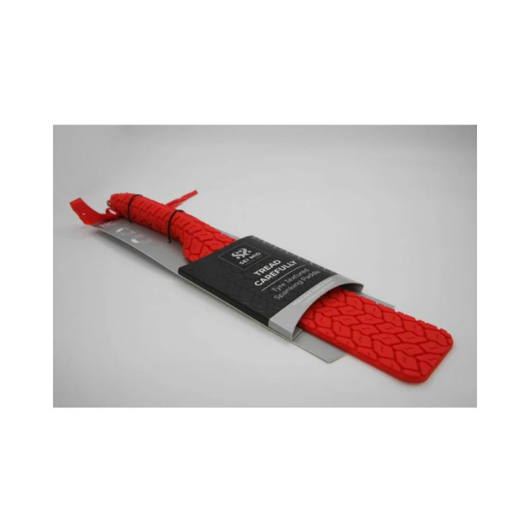 Red silicone paddle with textured tread pattern and black label on white background.