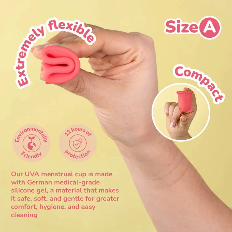 Hand holding a pink menstrual cup, showing its flexibility and compact size against a light background.